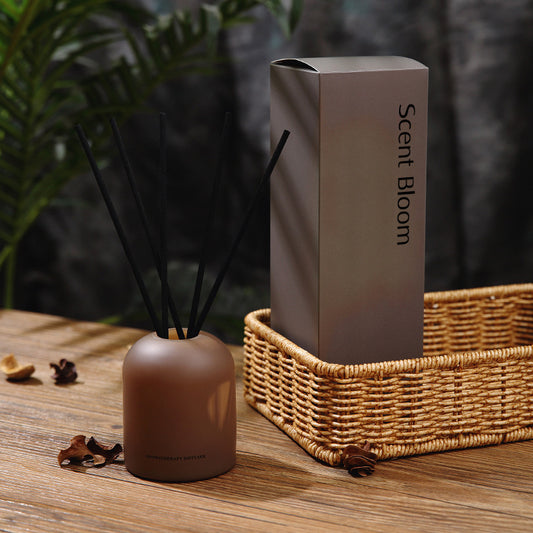Scent Bloom diffuser and packaging on a wooden surface with plants in the background