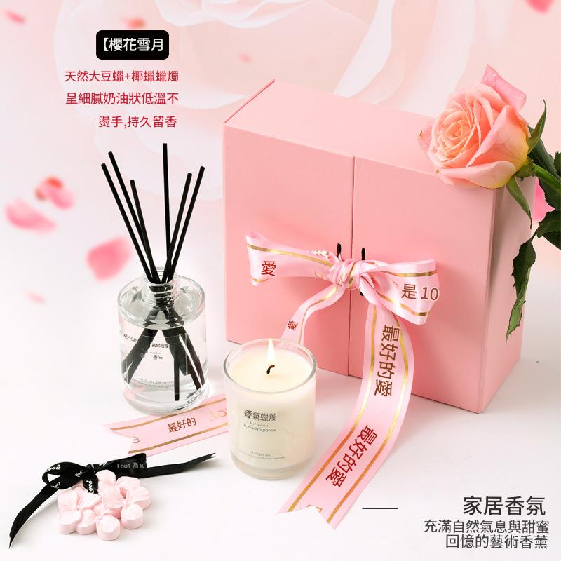 Candle, diffuser, and pink gift box with decorative elements on a light background