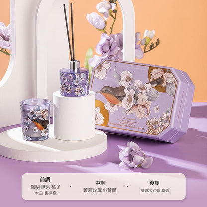 Decorative set with floral diffuser, glass, and packaging on a purple surface.
