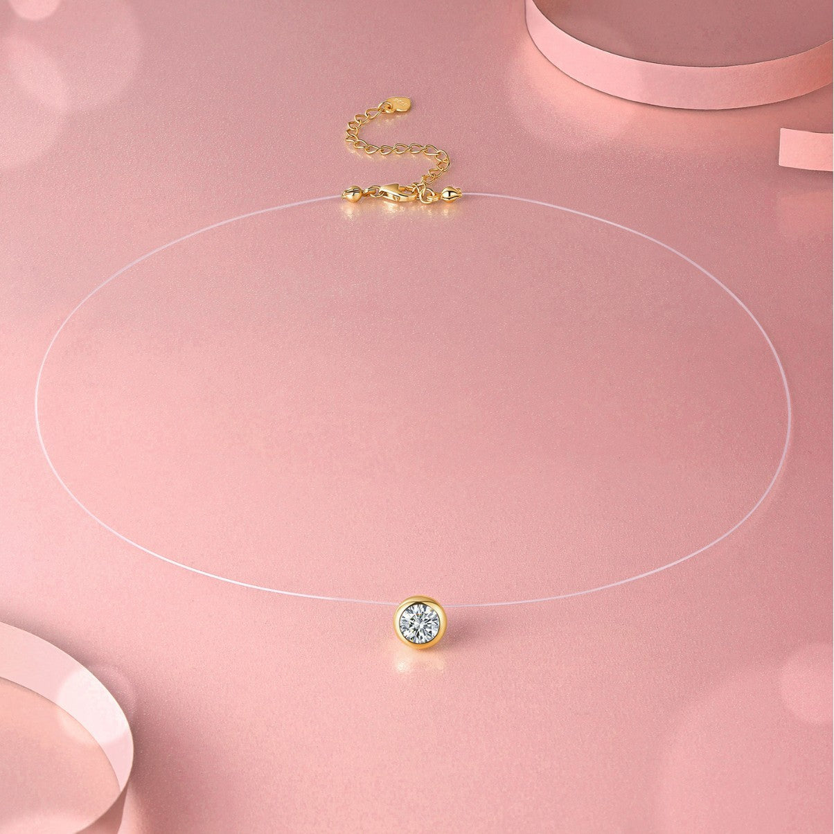 Gold necklace with a round pendant on a pink background