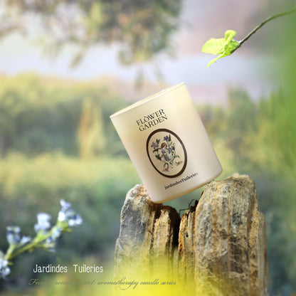 Candle labeled 'Flower Garden' by Jardindes Tuileries on a wooden stump with a blurred natural background.