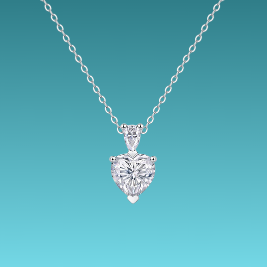 Heart-shaped diamond pendant on a chain against a teal background