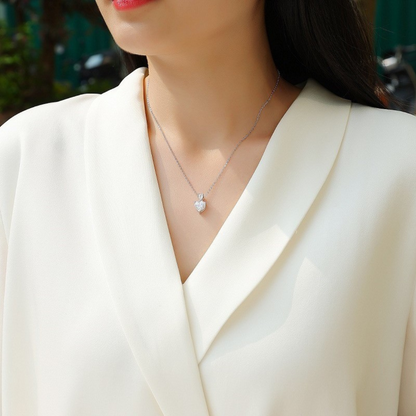 Woman wearing a silver necklace with a pendant against a blurred background