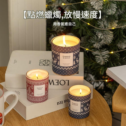 Three scented candles on a table with a Christmas tree in the background