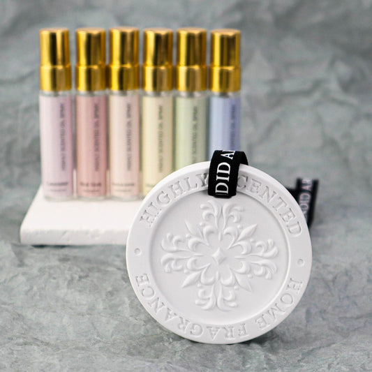 Set of perfume bottles with gold caps and a decorative white disc on a gray background