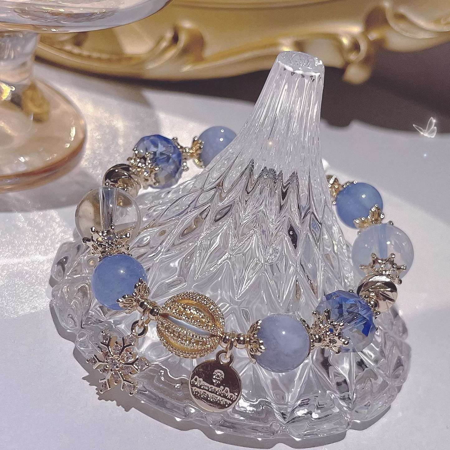Decorative crystal dish with blue and gold beads on a white surface