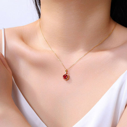 Gold necklace with a red pendant on a model wearing a white top