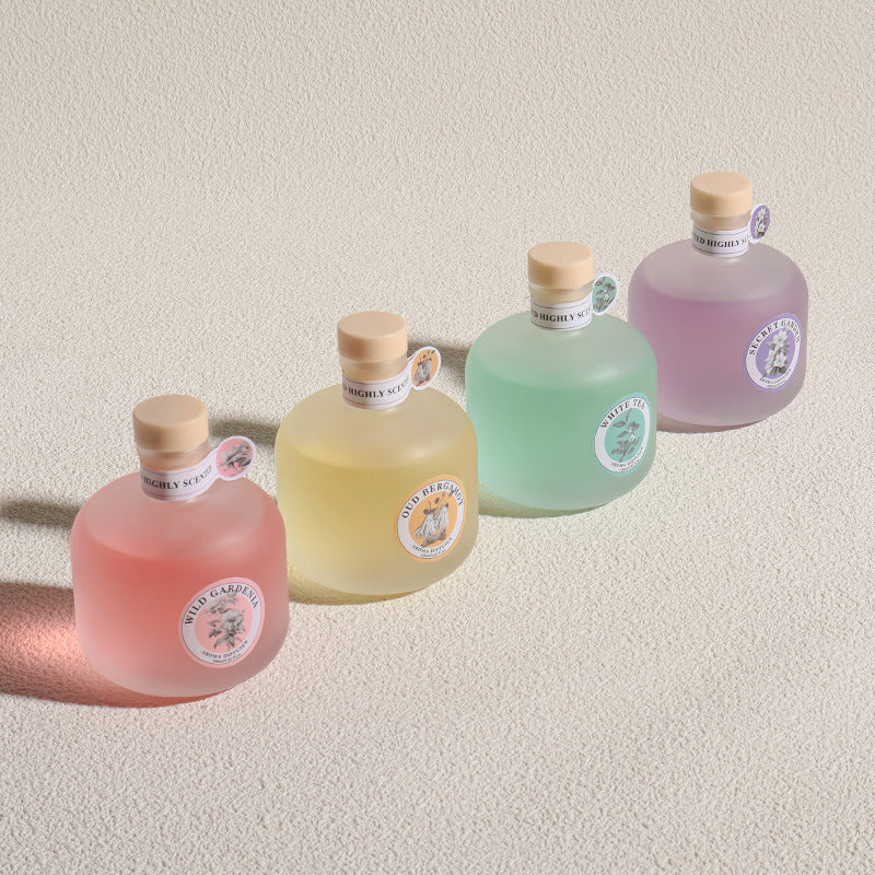 Five bottles of Wild Garden gin in different colors on a beige background
