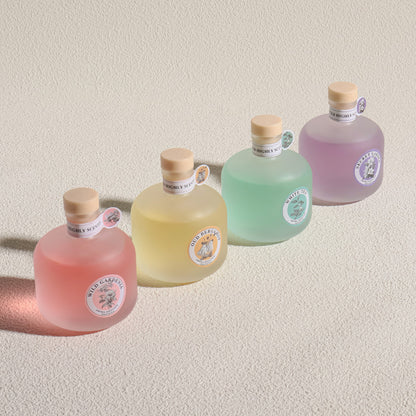 Five bottles of Wild Garden gin in different colors on a beige background