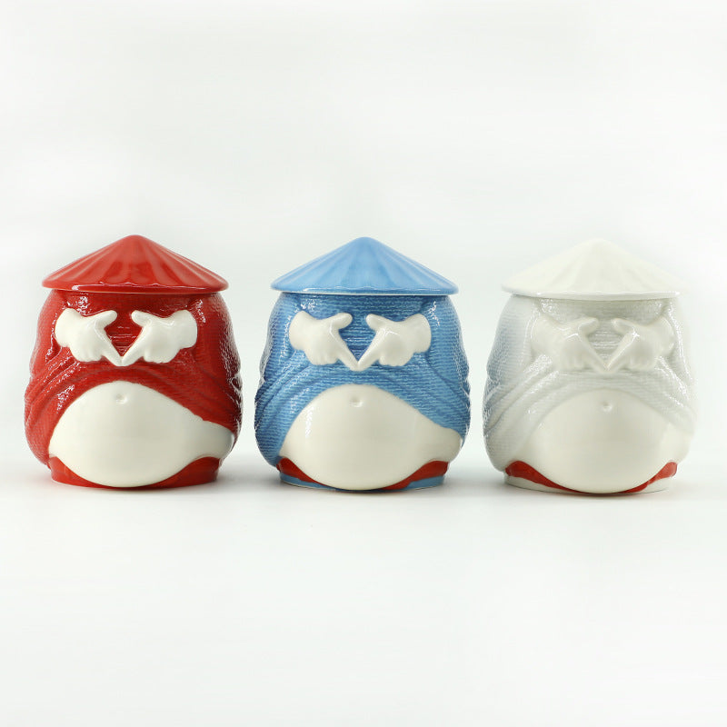 Three ceramic whale-shaped containers in red, blue, and white on a white background