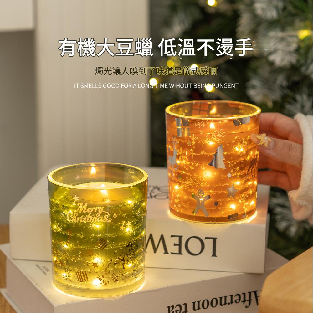 Two lit candles in glass containers with decorative designs on a white surface.