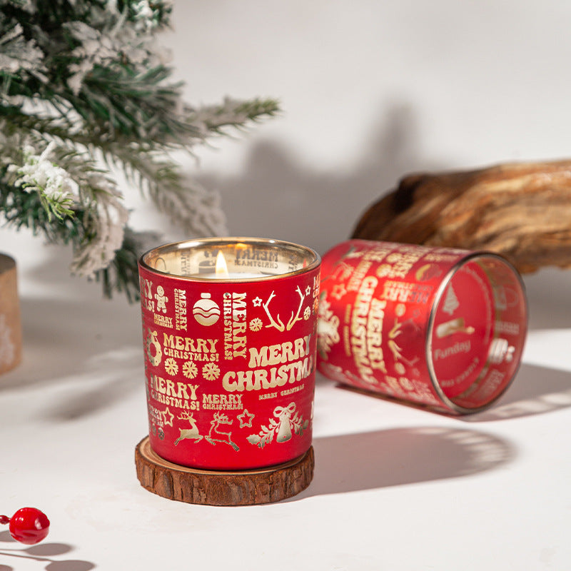 Red Christmas-themed candle with decorative patterns on a white surface with a blurred background