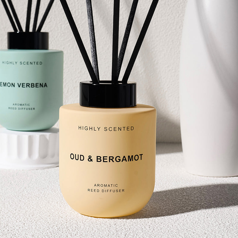 Reed diffuser labeled 'Oud & Bergamot' next to a green diffuser labeled 'Lemon Verbena'.