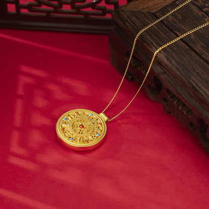 Gold necklace with a decorative pendant on a red surface