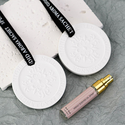 White aroma sachets with black text and a pink oil spray bottle on a gray surface