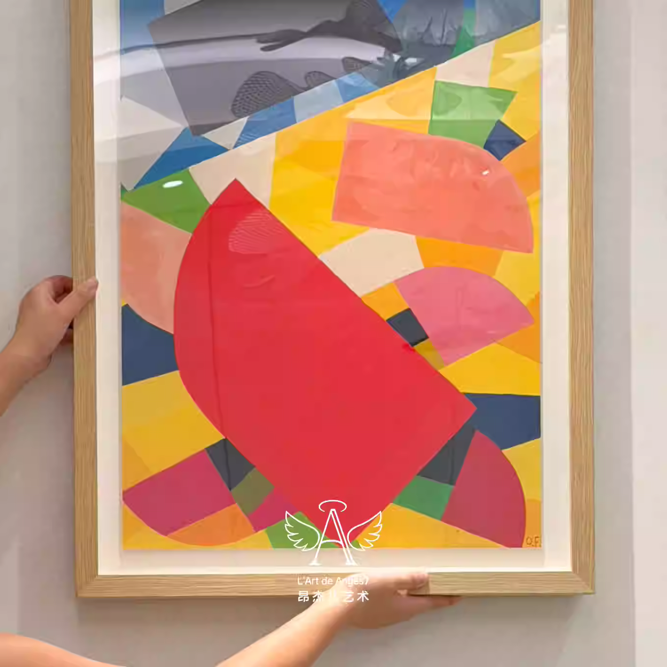 Colorful abstract art piece with geometric shapes being held by a person against a white wall.