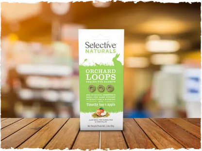 Selective Naturals Orchard Loops pet food package on a wooden surface with a blurred background