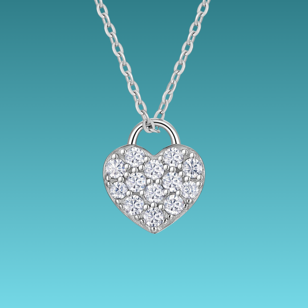 Heart-shaped silver necklace with clear stones on a teal background