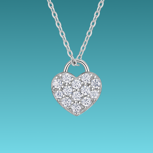 Heart-shaped silver necklace with clear stones on a teal background