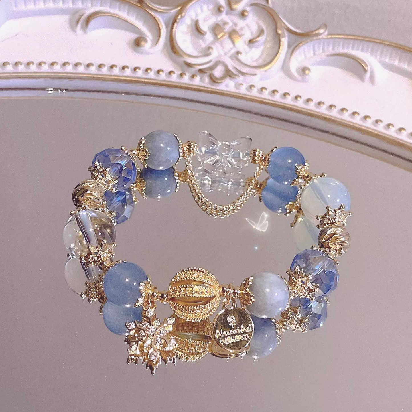 Bracelet with blue beads and gold accents on a decorative mirror background