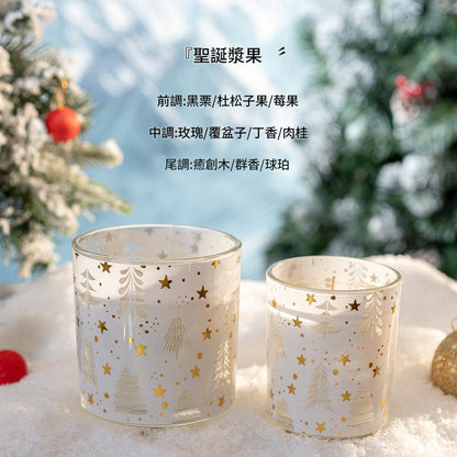 Two glass candle holders with Christmas tree and star patterns on a snowy surface with blurred Christmas trees in the background.