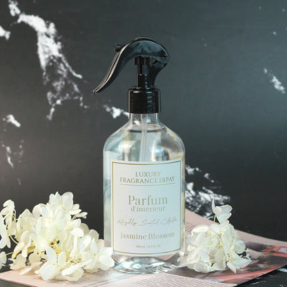Luxury fragrance spray bottle labeled 'Parfum d'Intérieur Jasmine Blossom' with white flowers on a dark background