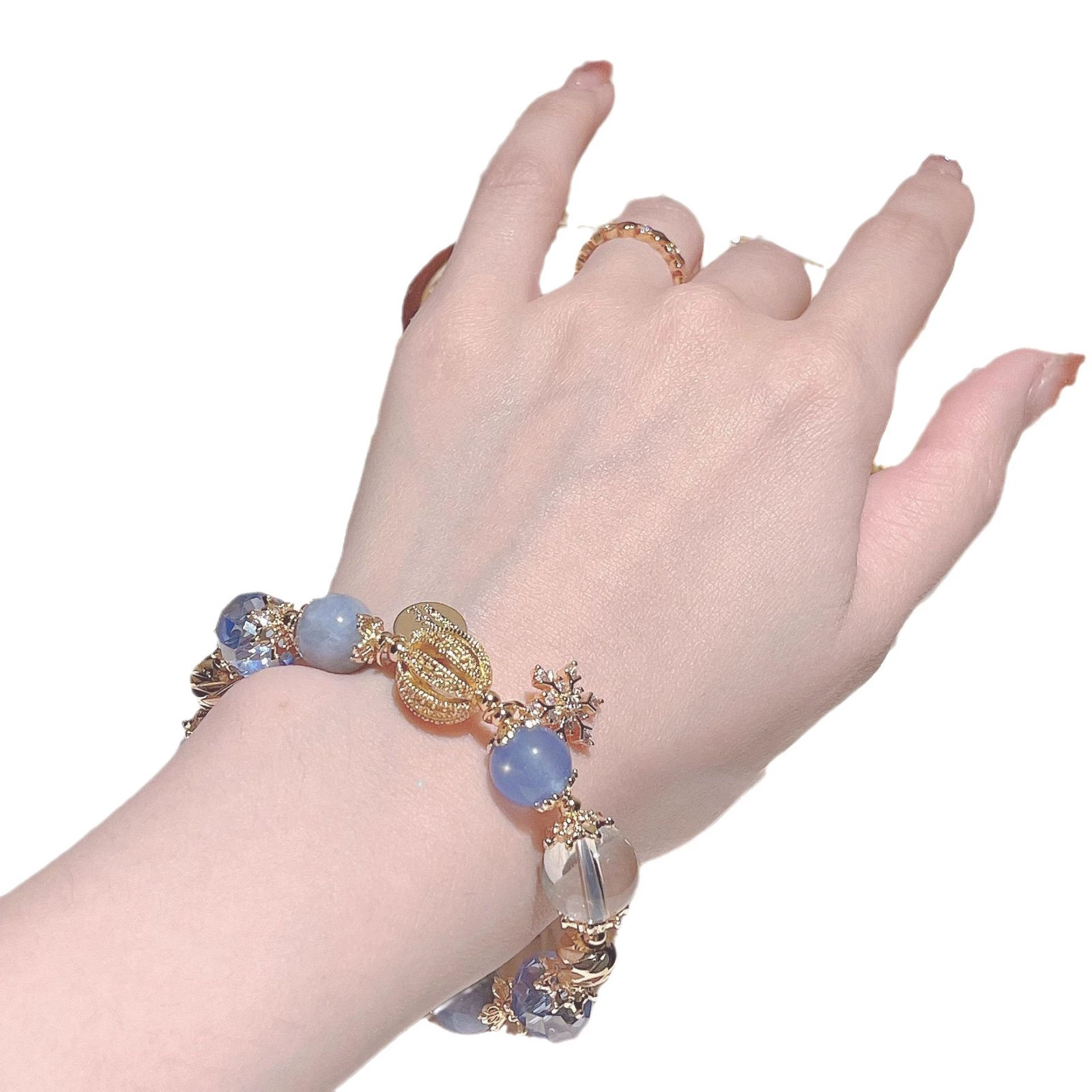 Hand wearing a decorative bracelet with blue beads and gold accents on a white background