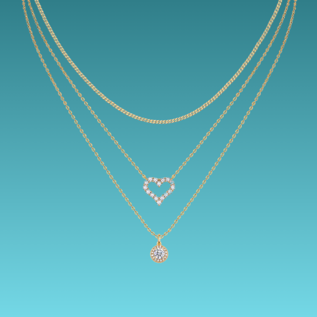 Two gold necklaces with heart and round pendants on a teal background