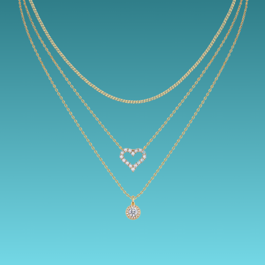 Two gold necklaces with heart and round pendants on a teal background