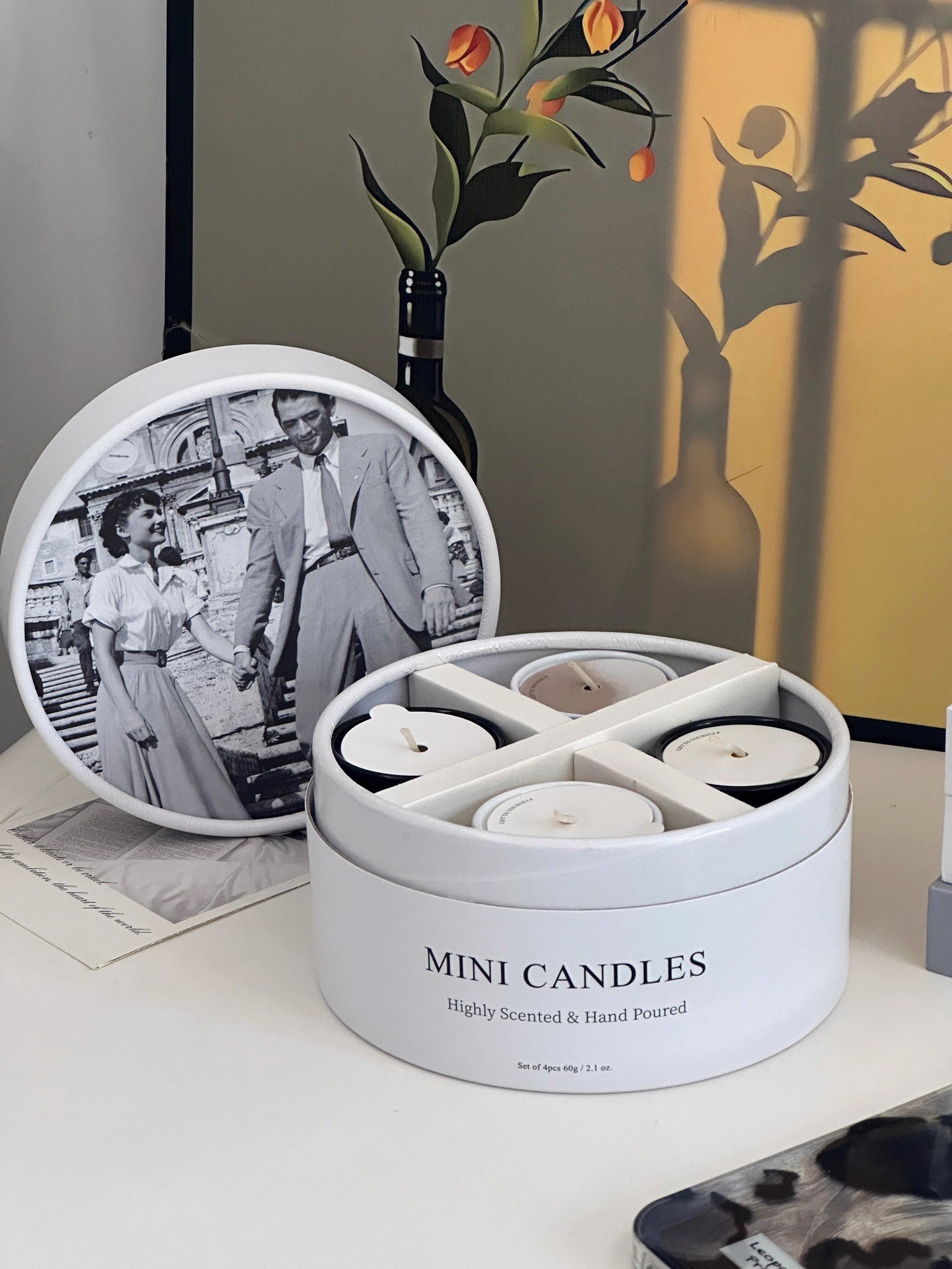 Set of mini candles in a round container with a vintage photo and decorative items in the background.