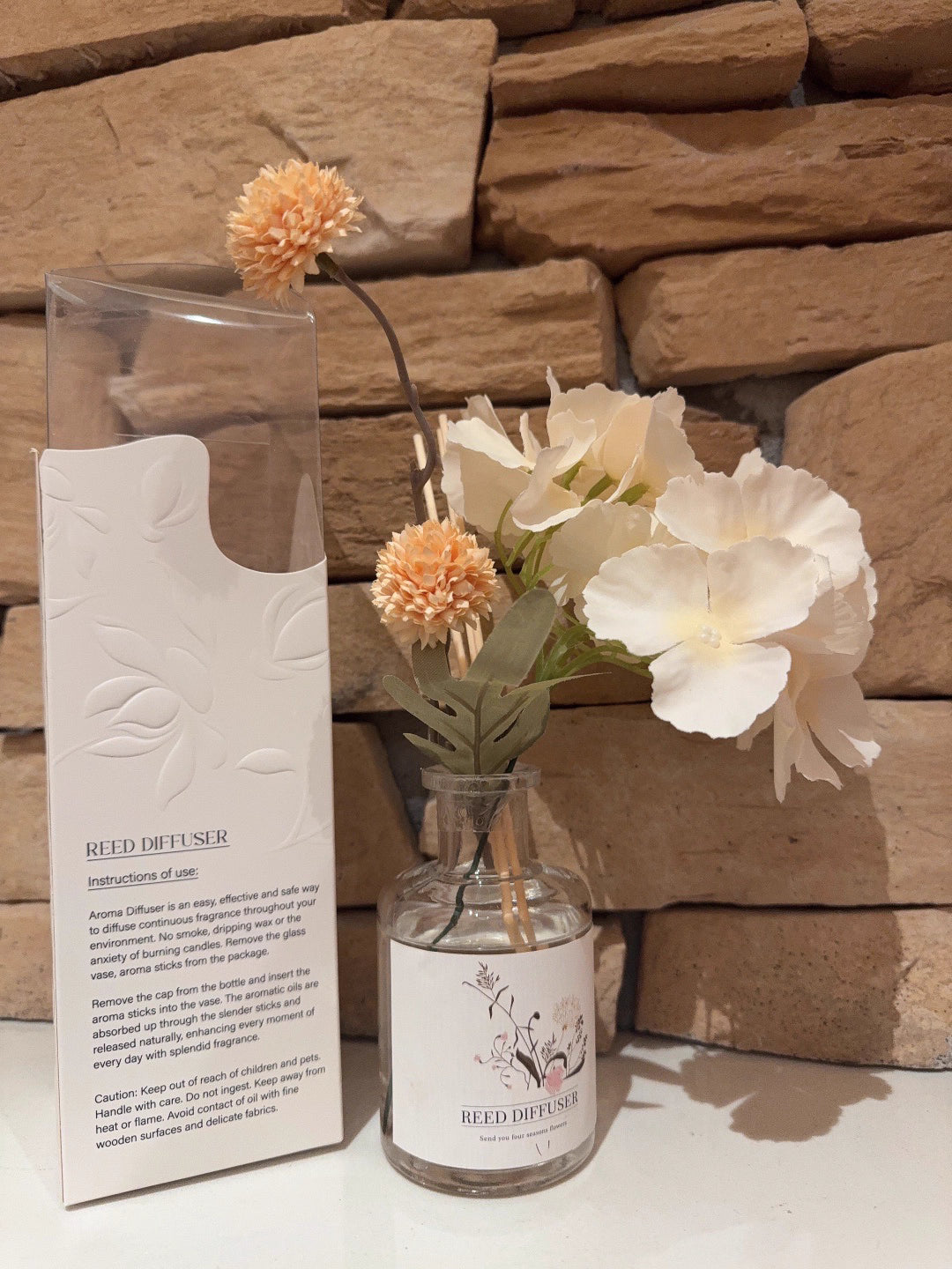 Reed diffuser with flowers against a stone wall background