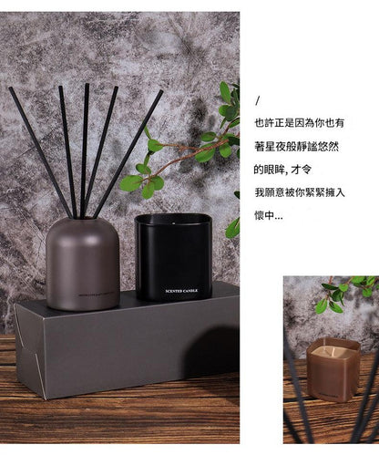 Decorative diffuser with black sticks and a black candle on a wooden surface with a textured gray wall background.