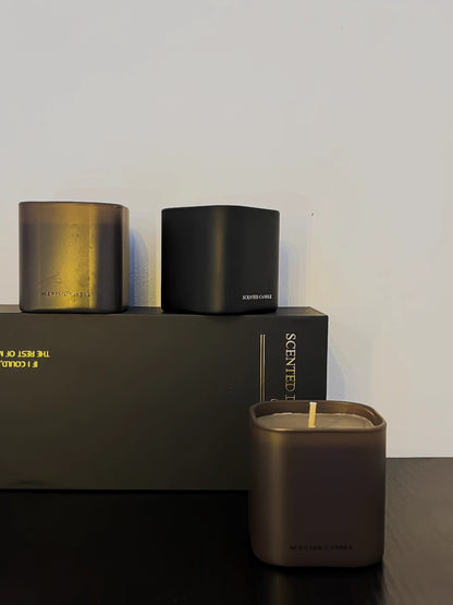 Three candles of different sizes on a dark surface with a plain background