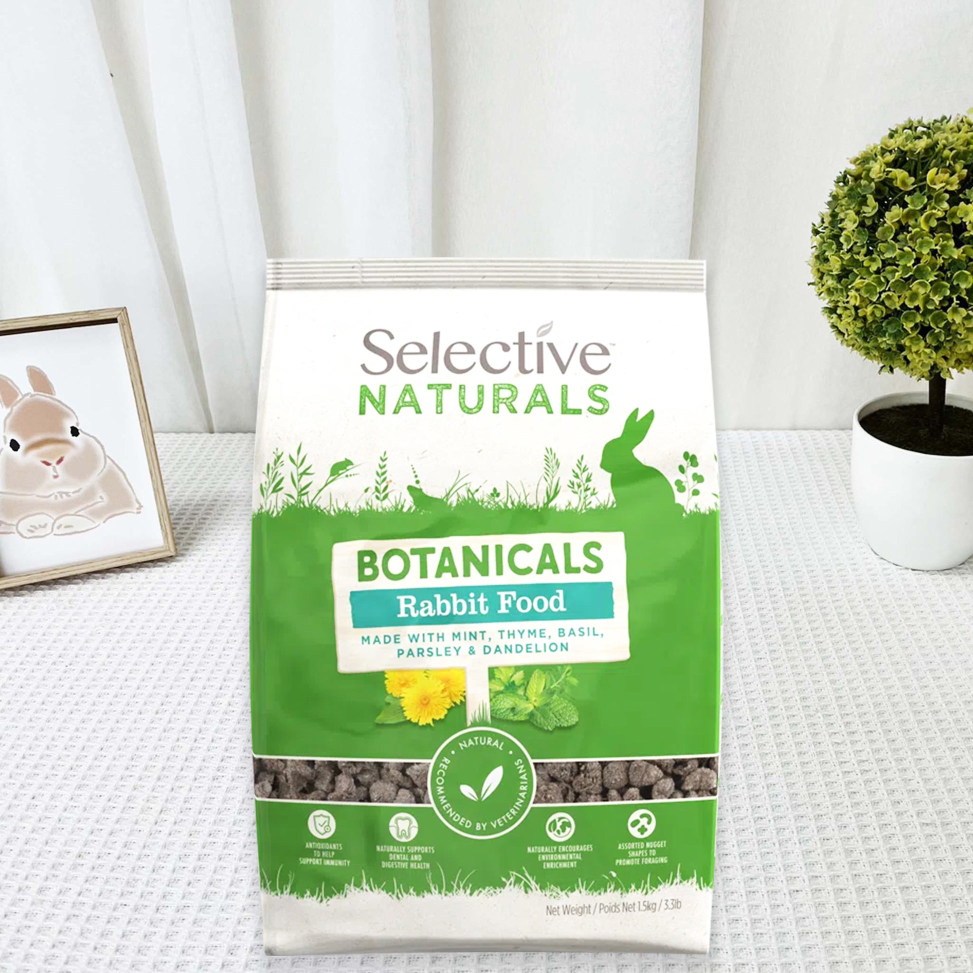 Bag of Selective Naturals Botanicals Rabbit Food on a white surface with a plant and rabbit illustration in the background.