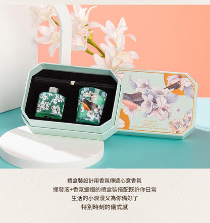 Two small bottles in a decorative box with floral design on a light blue surface.