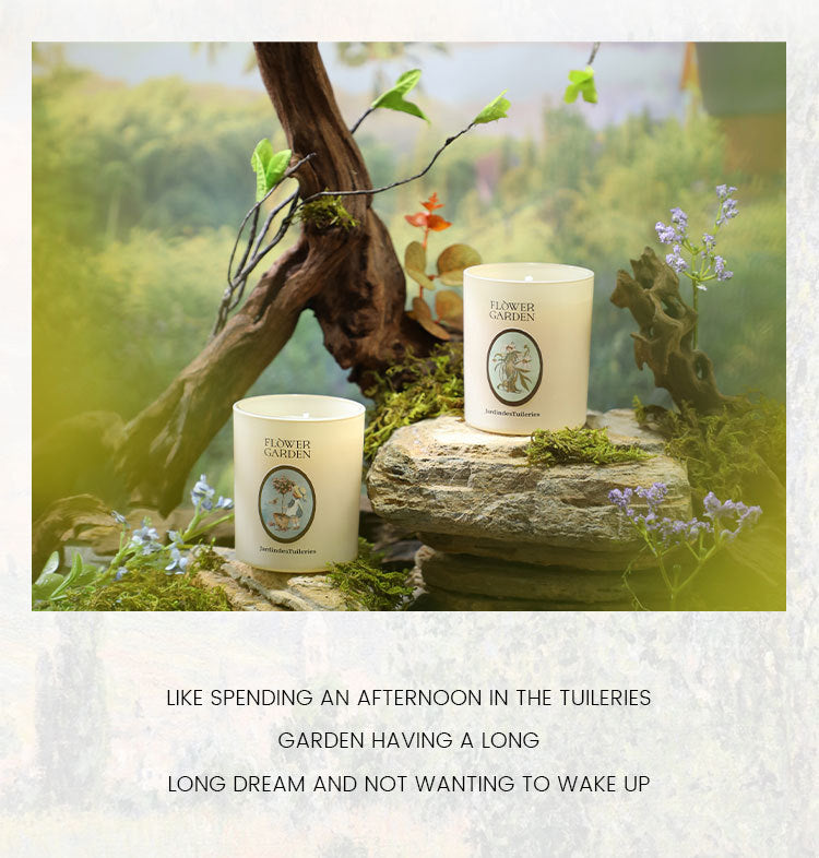 Two candles on a stone surface with nature-themed packaging in a garden setting.
