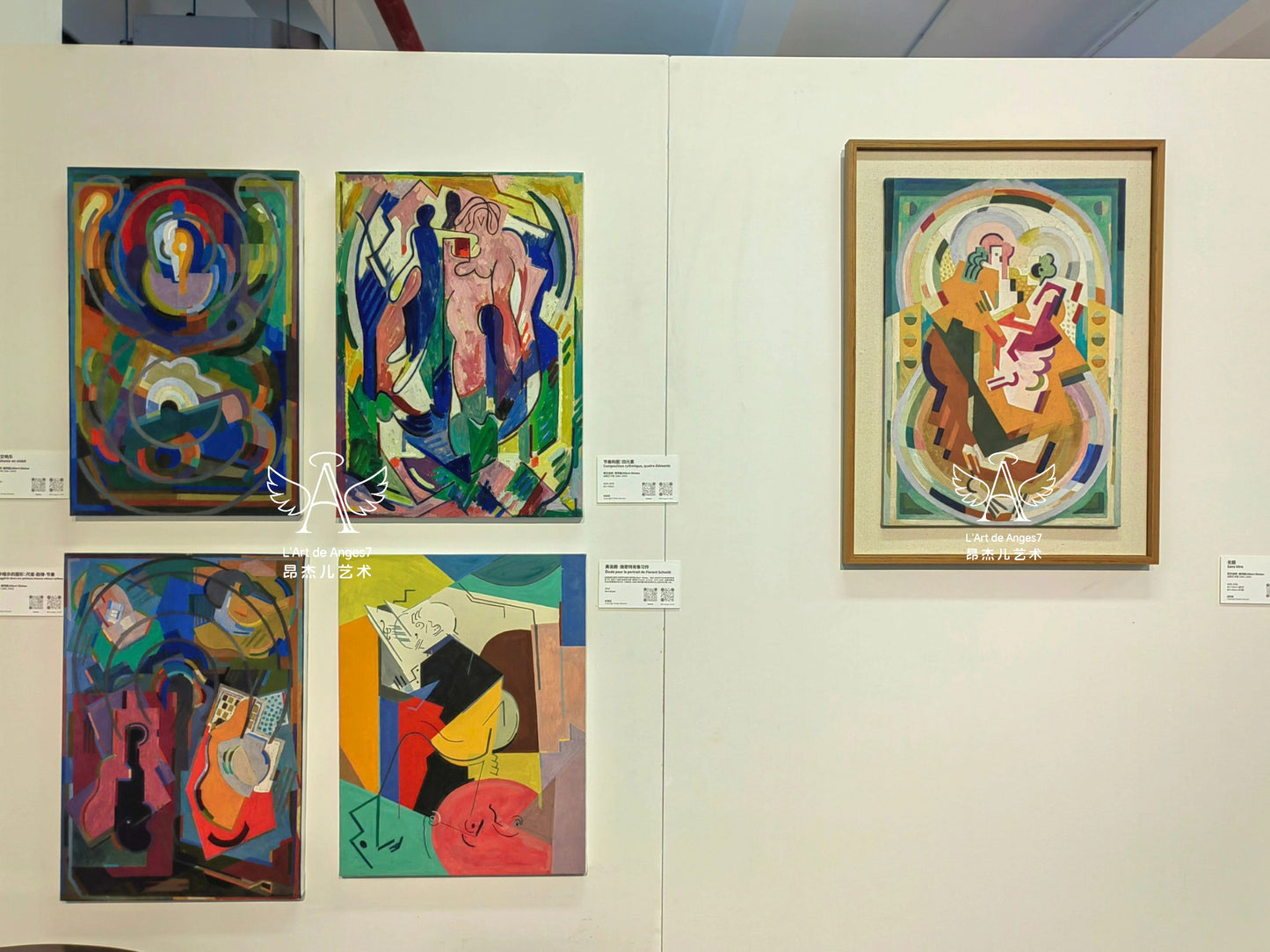 Collection of abstract paintings displayed on a wall with labels.
