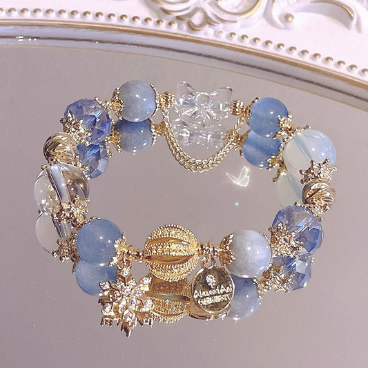 Bracelet with blue beads and gold charms on a reflective surface